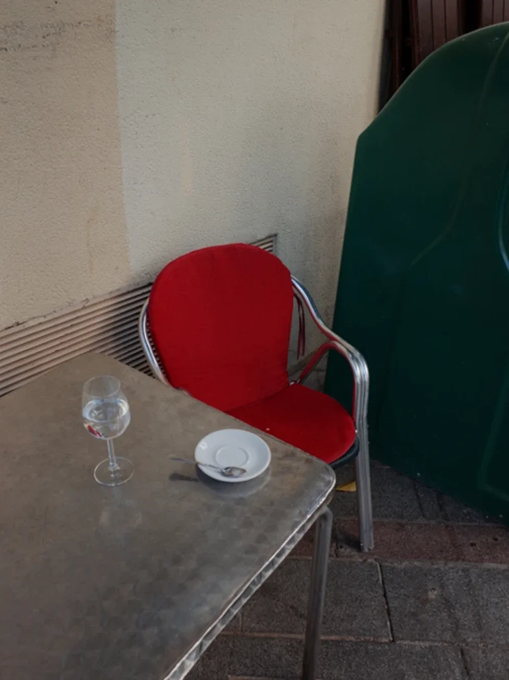 Cantes de ida y vuelta, de Ana Suanes: silla roja junto a una mesa de terraza con una copa y un plato vacío